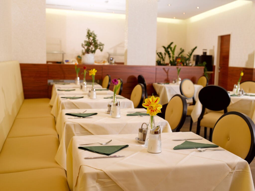 Gemütlicher Speiseraum im Hotel 3Raben Graz mit elegant gedeckten Tischen, frischen Blumen und modernem Ambiente.